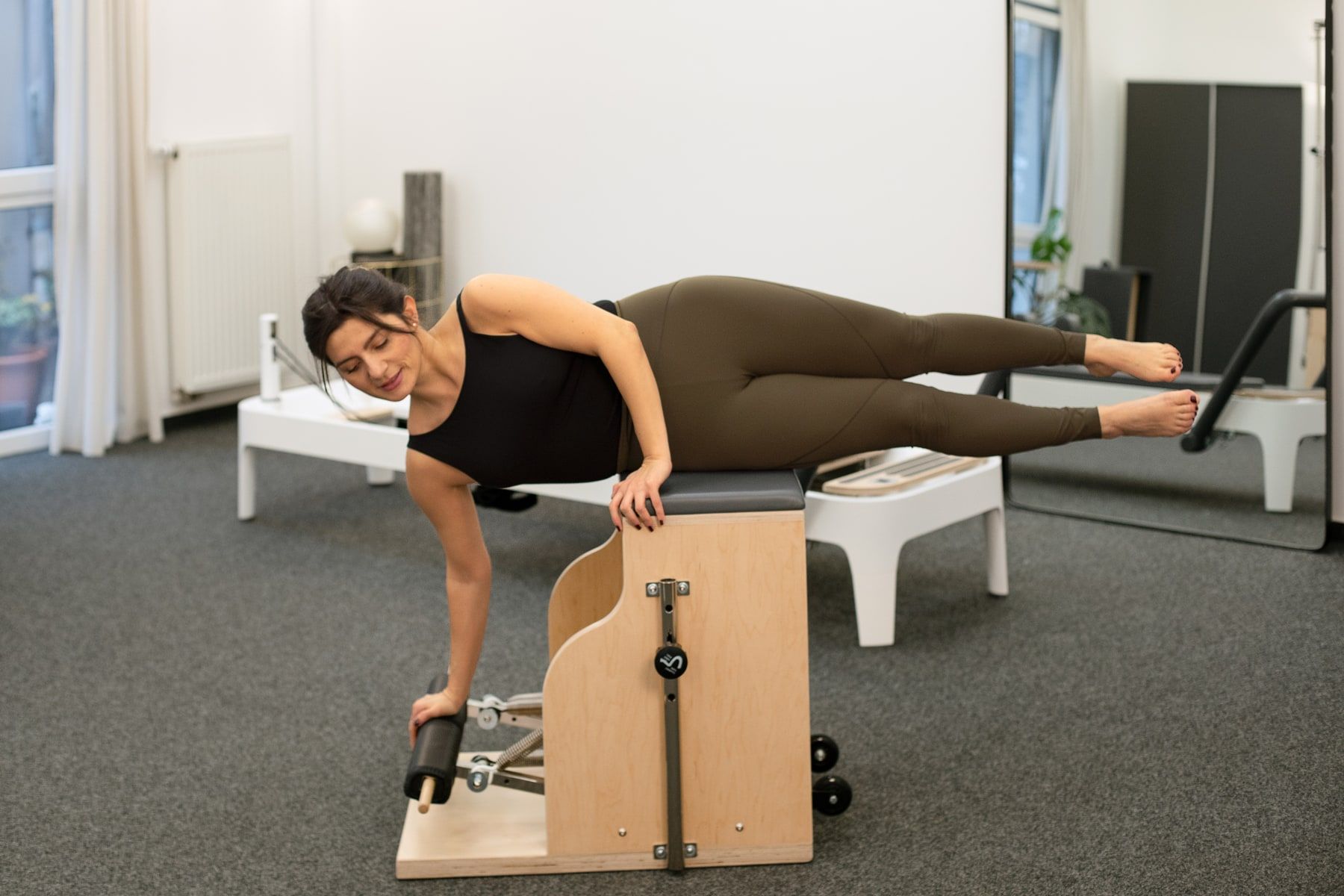 Pilates Trainerin performt Übung auf dem Pilates Chair